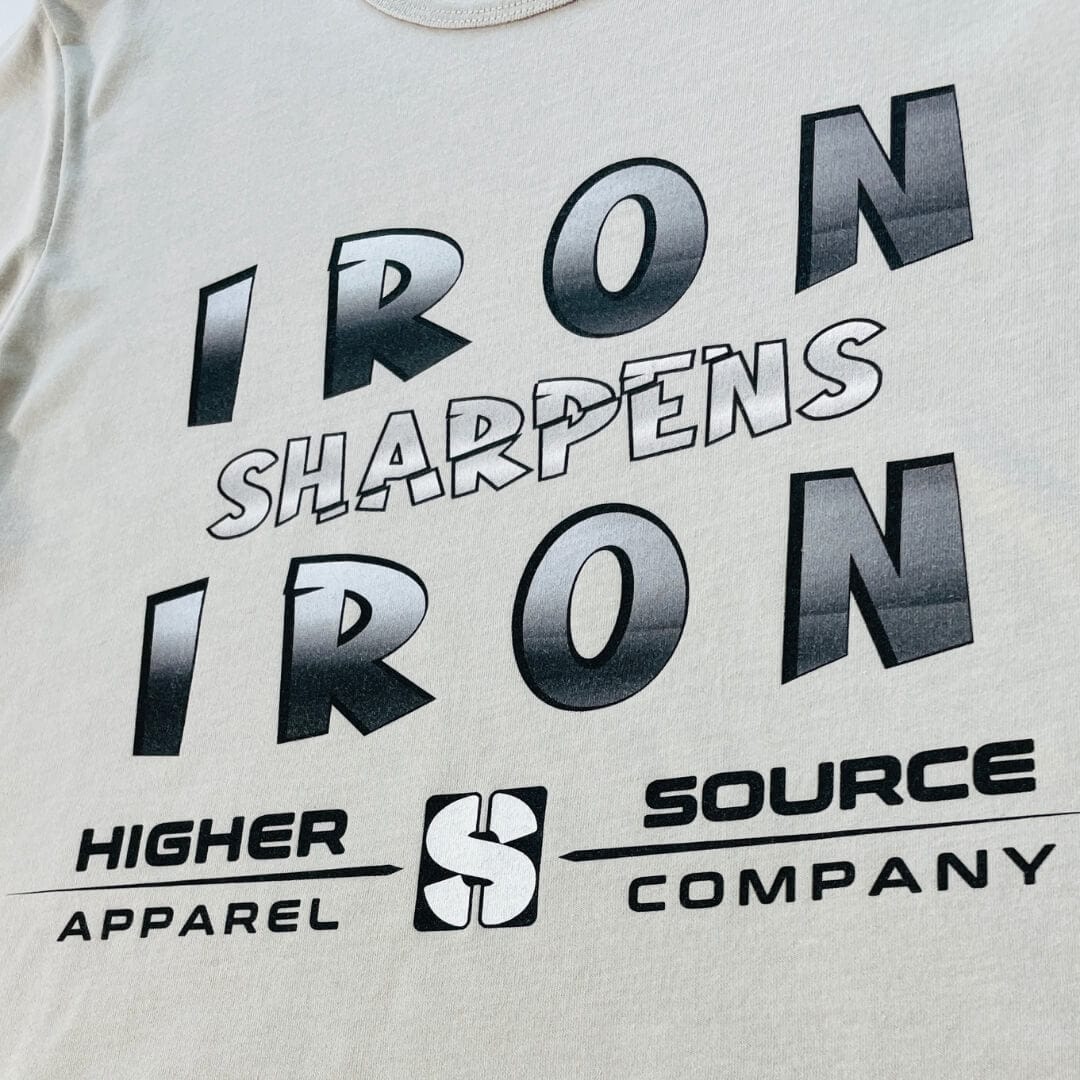 Iron sharpens iron in large black and american silver font. Higher source apparel company is written in black font below