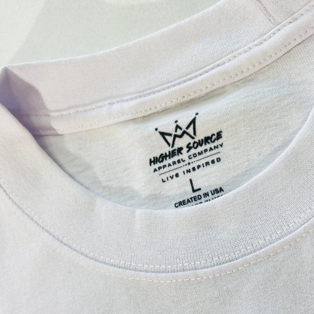 A close up of a higher source neck tag and collar. The label says designed to inspire in black font